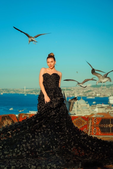 A person in a black dress with a cityscape and birds in the background. 5