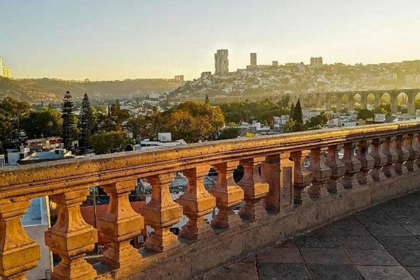 A stone bridge with ornate balustrades, a cityscape in the background, and a clear sky. 4