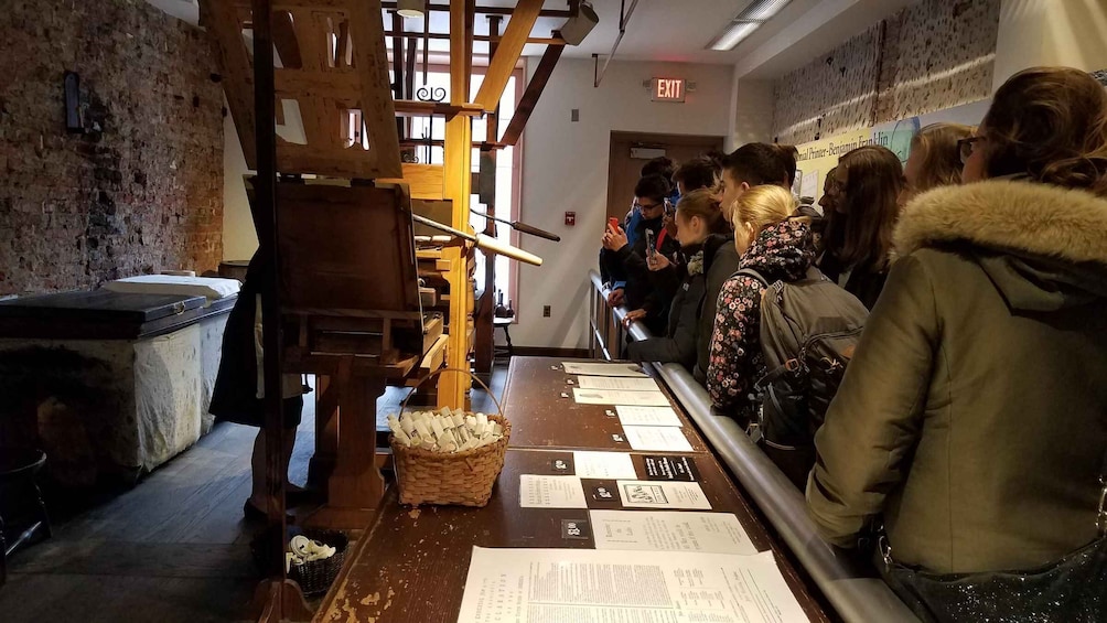 A queue of people at a counter with papers and a wooden structure. 5