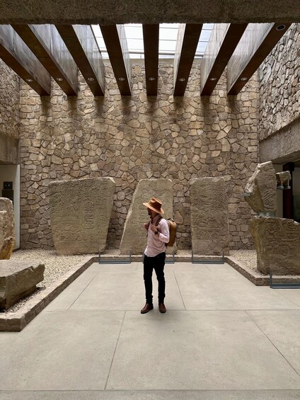 A person standing in a stone courtyard with a modern roof structure. 3