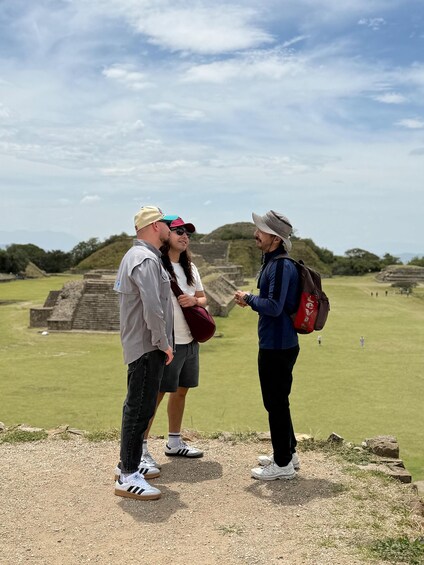 Three people standing on a grassy hill overlooking ancient ruins. 2
