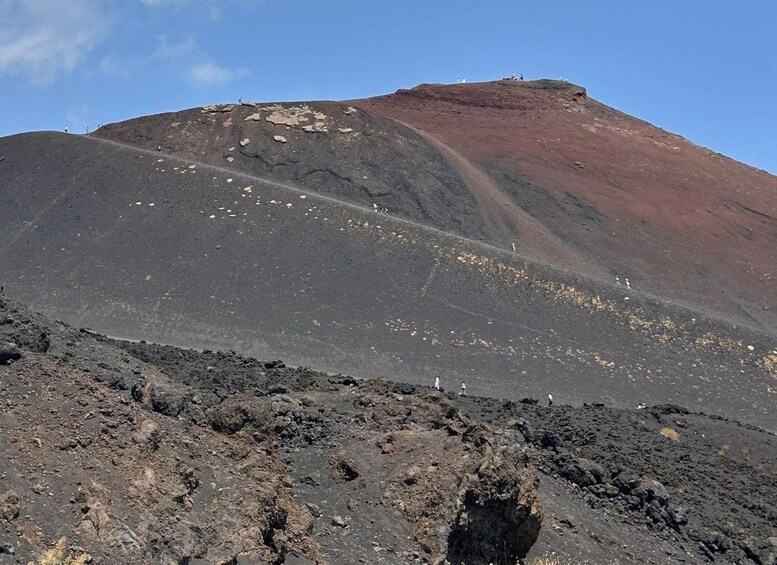 A volcanic landscape with a prominent crater and a reddish-brown slope. 2
