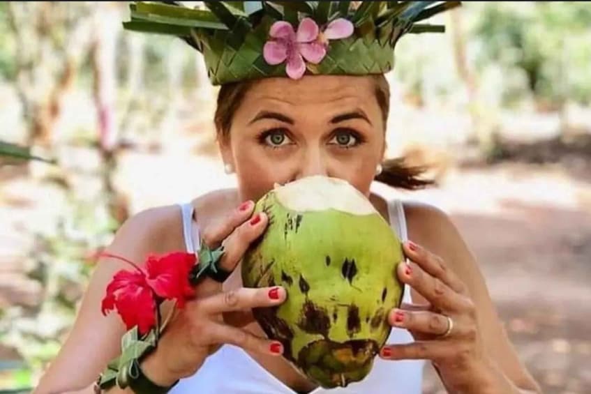 A person holding a green coconut with a flower on top. 2