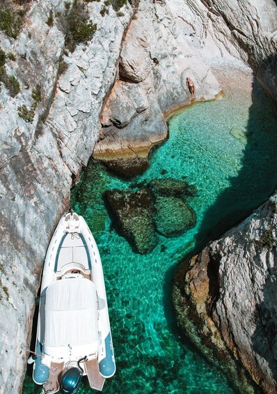 A boat anchored near a rocky shoreline with clear turquoise water. 1