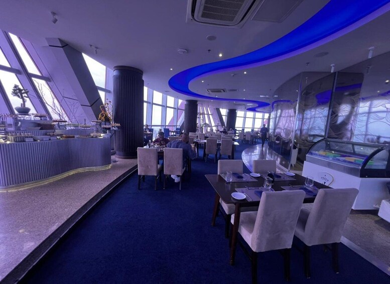A modern restaurant interior with blue lighting, high ceilings, and a central bar area. 5