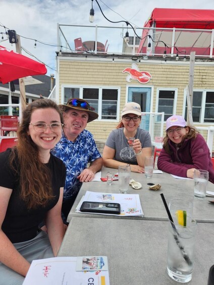 Four people sitting at an outdoor table with drinks and a menu. 1