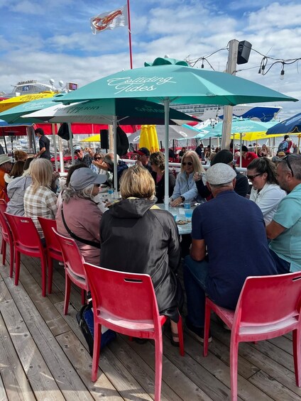 People dining at an outdoor restaurant with red chairs and green umbrellas. 4