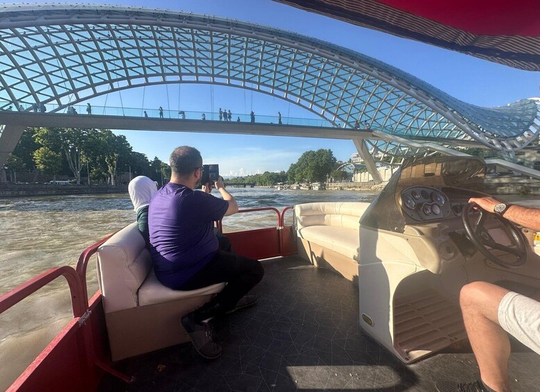 A boat with a person taking a photo of a bridge. 5