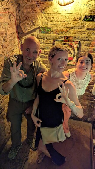 Three people posing in front of a wall covered with graffiti. 4