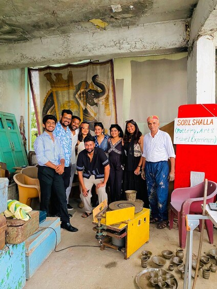 A group of people in a workshop with pottery and art equipment. 1