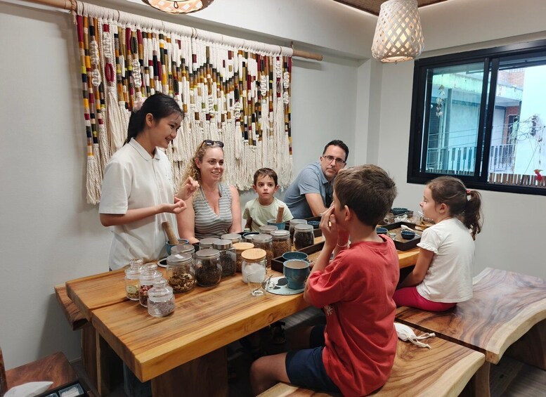 A group of people engaged in a craft activity with various jars and containers on a wooden table. 2