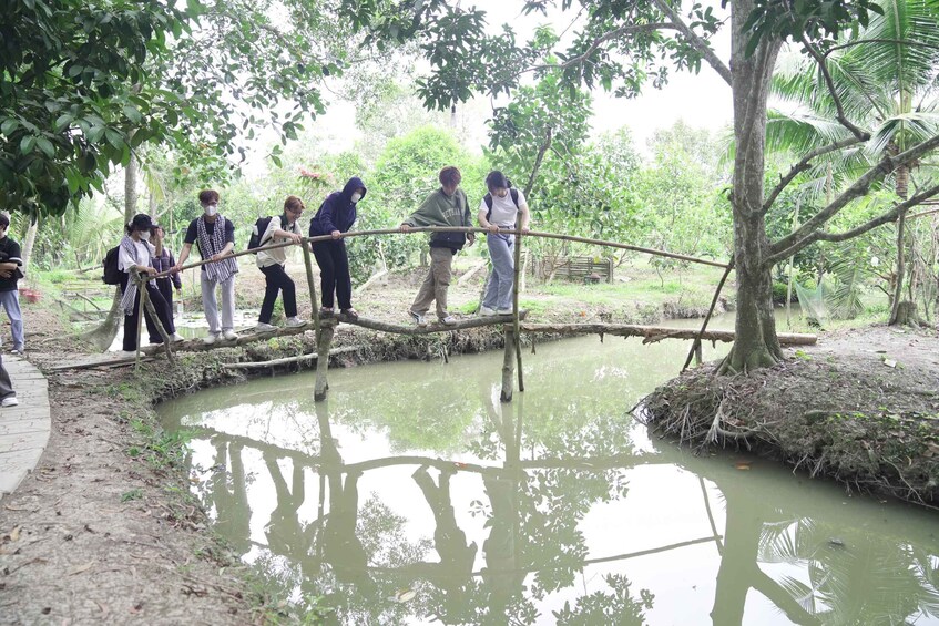 Un grupo de personas cruzando un pequeño cuerpo de agua utilizando un puente improvisado. 4