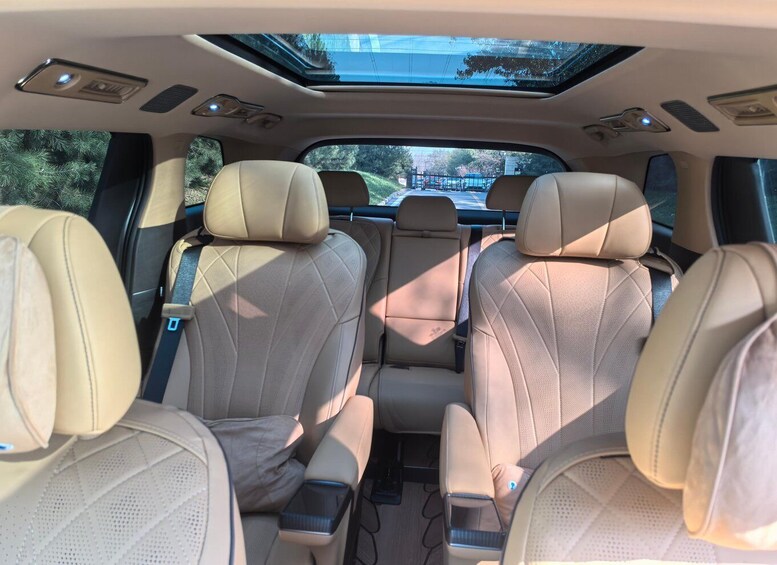 A car's interior with beige leather seats, a sunroof, and a rearview mirror. 4