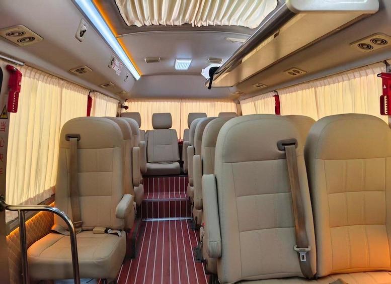 A train interior with beige seats, red-striped floor, and curtains. 2