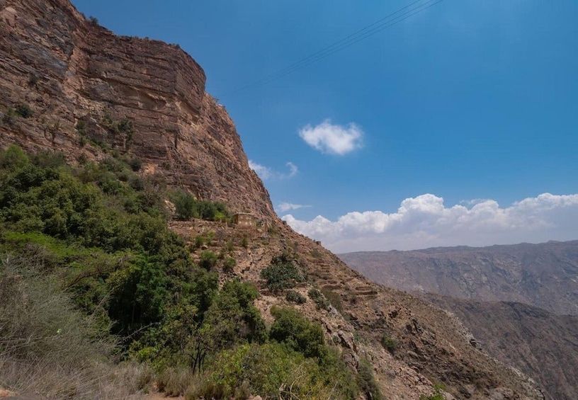 A rugged mountain landscape with a clear sky and a small building on the slope. 2