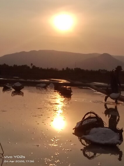 A sunset over a calm water body with mountains in the background. 1