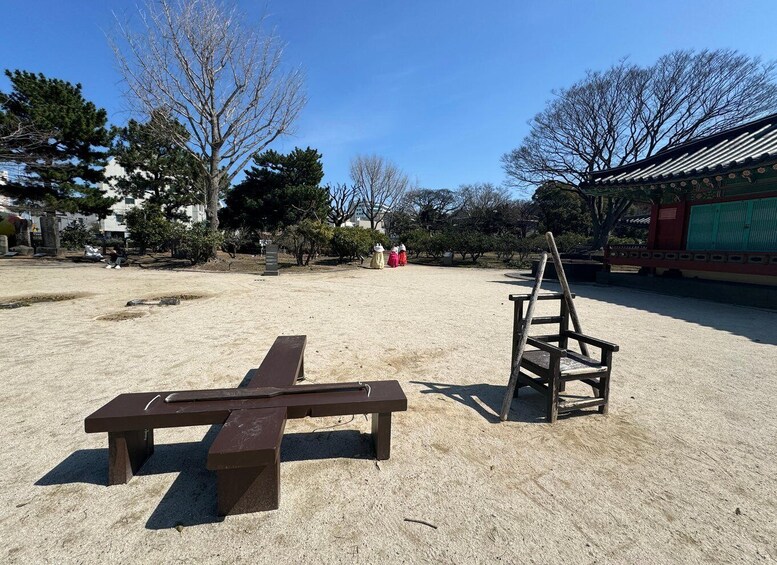 A picnic area with benches and a wooden structure, surrounded by trees and buildings. 4