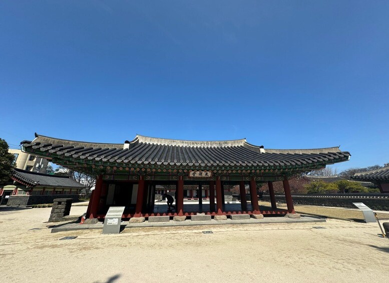 A traditional Korean pavilion with a tiled roof and red pillars. 2
