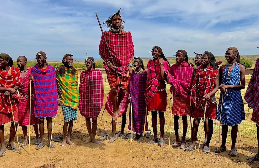 A group of people in traditional attire standing in a natural landscape. 3