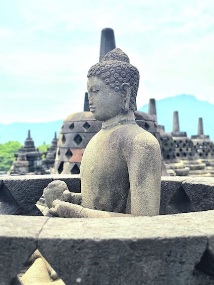 A stone Buddha statue in a temple setting with traditional architecture in the background. 5