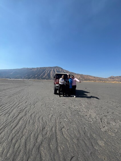 A desert landscape with a vehicle and three people. 2