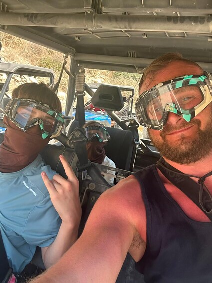 Two people in a vehicle wearing safety goggles. 4