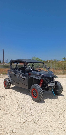 A black off-road vehicle with red wheels parked on a sandy surface. 2
