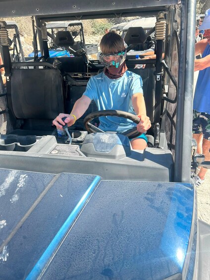 A person driving a golf cart with a steering wheel and a water bottle on the dashboard. 5