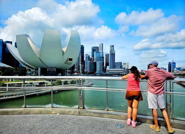 A couple overlooking a modern architectural structure and a city skyline. 3