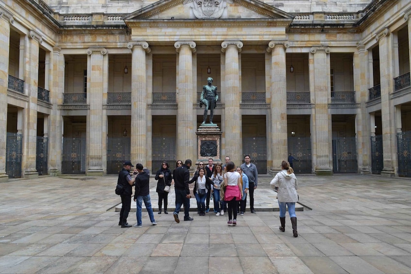 A group of people gathered in a courtyard with a statue in the center. 1