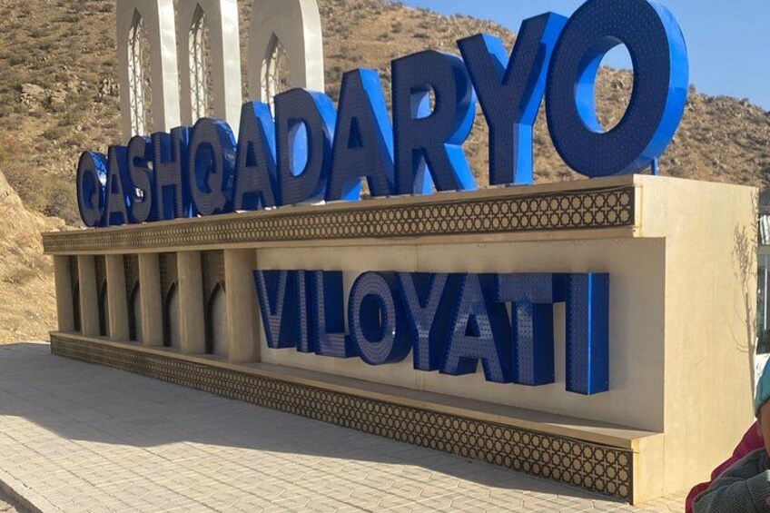 Une grande enseigne avec les mots « CASHADARYO » et « VILOYATI » écrits en lettres bleues. 2