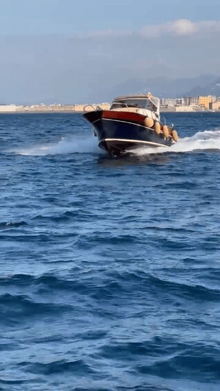 A speedboat moving across a body of water with a coastal cityscape in the background. 3