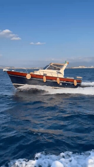 A speedboat moving across a body of water with a clear sky and distant land in the background. 4