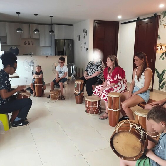 A group of people sitting on stools, playing drums in a modern interior space. 3
