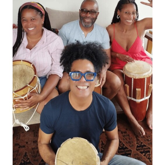 A group of people sitting on a patterned rug, holding drums. 5