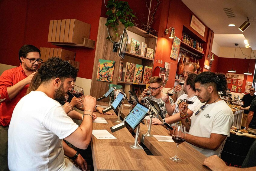 A group of people tasting wine at a bar with wooden shelves and artwork. 5