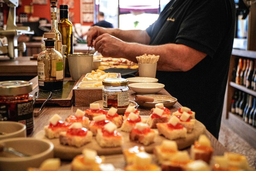 A person preparing food with various condiments and ingredients on a wooden table. 3