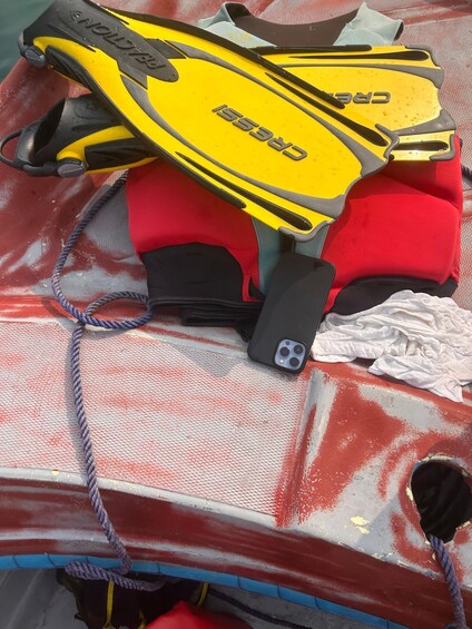 A red kayak with yellow and black fins, a black life vest, and a white cloth. 3