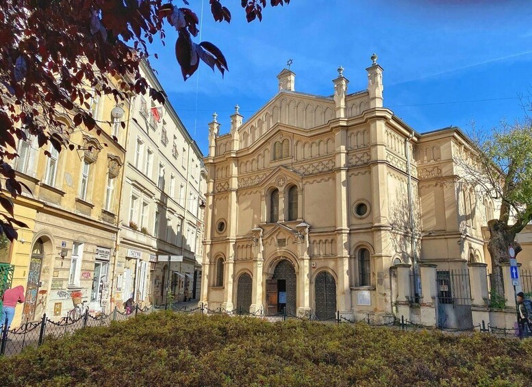 A historic building with ornate architecture, a clear blue sky, and a hedge in the foreground. 2