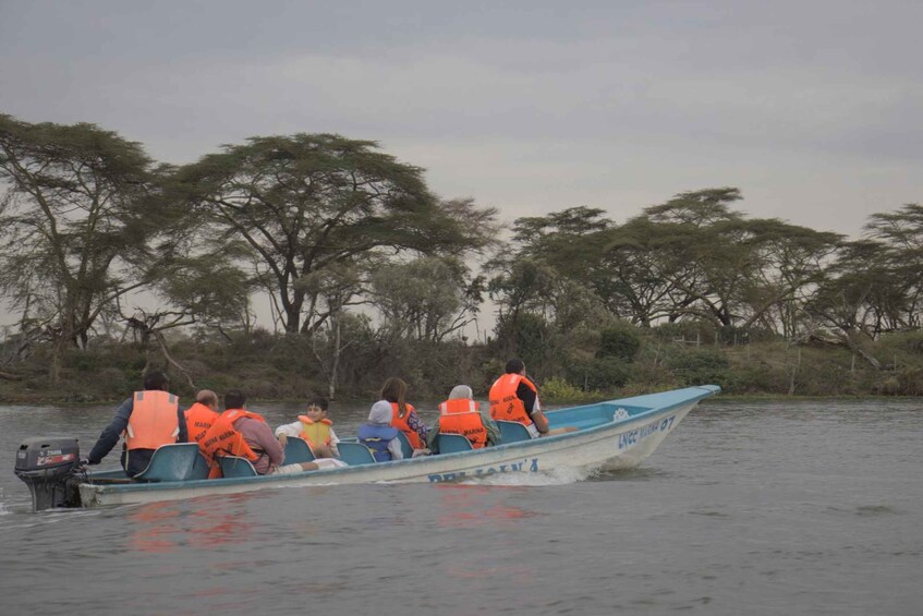 A boat with people wearing life jackets on a calm body of water, surrounded by trees. 2