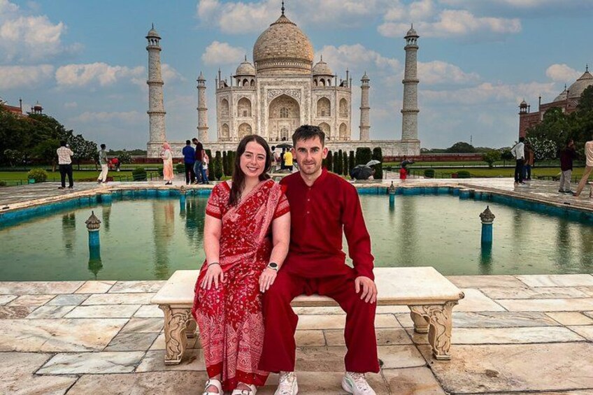 Een koppel zit op een bankje, met de Taj Mahal op de achtergrond. 1