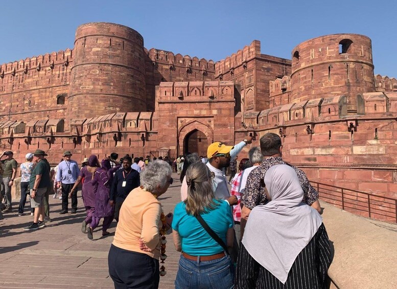 A historic fort with red brick walls and multiple towers, surrounded by a crowd of tourists. 4