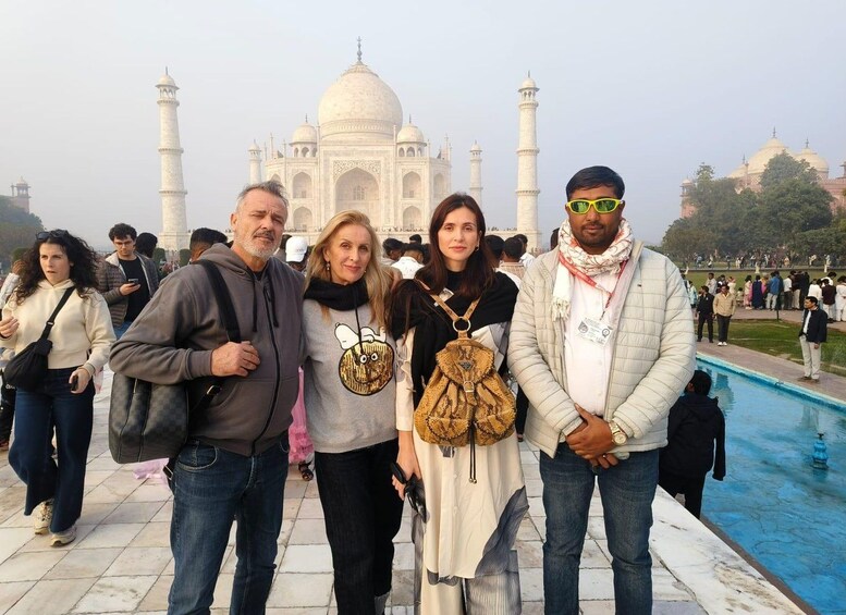 A group of people standing in front of the Taj Mahal with the pool to the right. 1