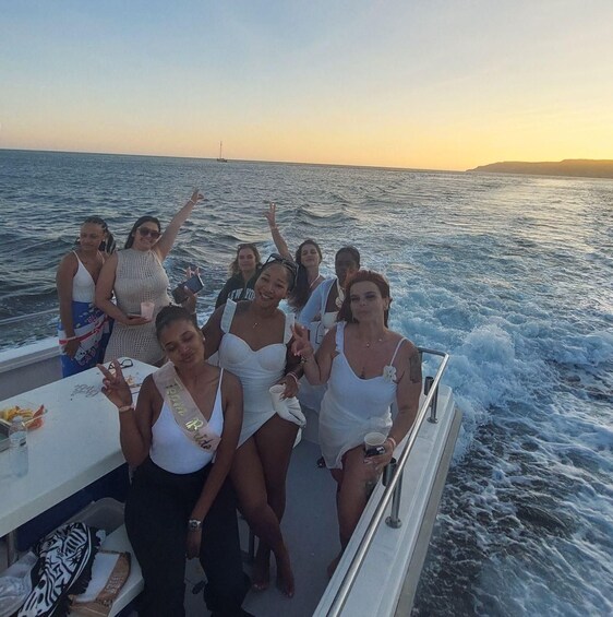 A group of people on a boat with a sunset in the background. 2