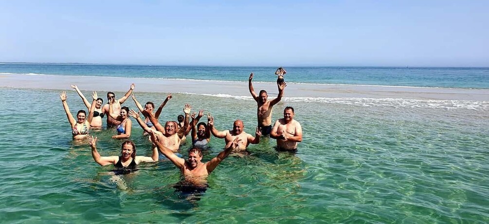 A group of people in the ocean, some raising their hands. 3