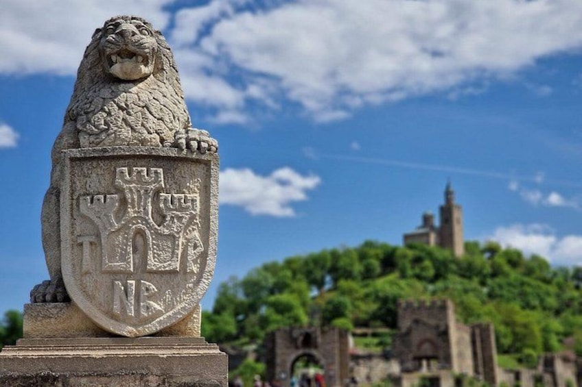Een standbeeld van een stenen leeuw met een familiewapen, een kasteel op de achtergrond en weelderig groen. 3