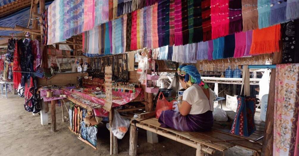 Un puesto de mercado con telas y textiles de colores exhibidos. 4