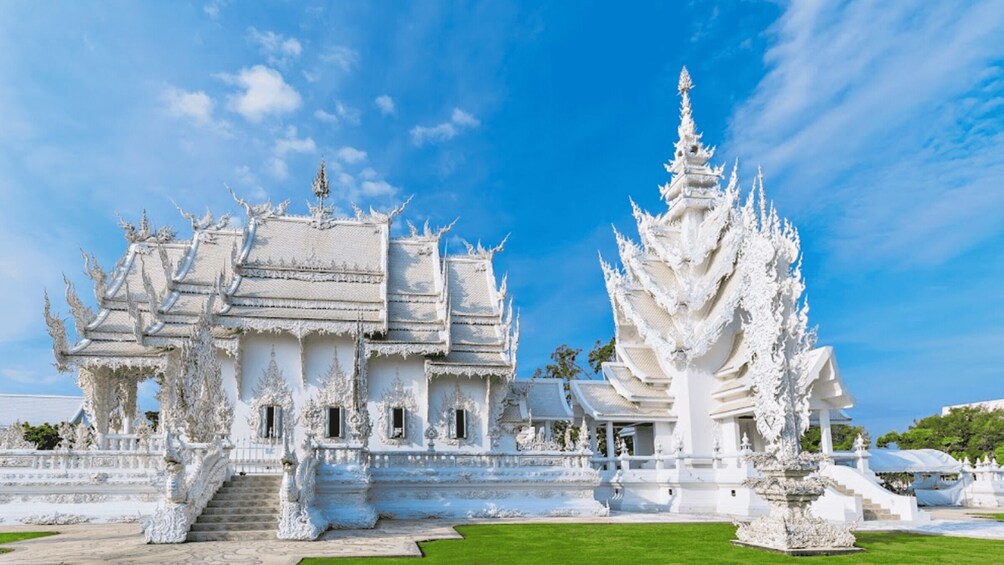 Un templo blanco ornamentado con tallas intrincadas y un gran árbol en primer plano. 2
