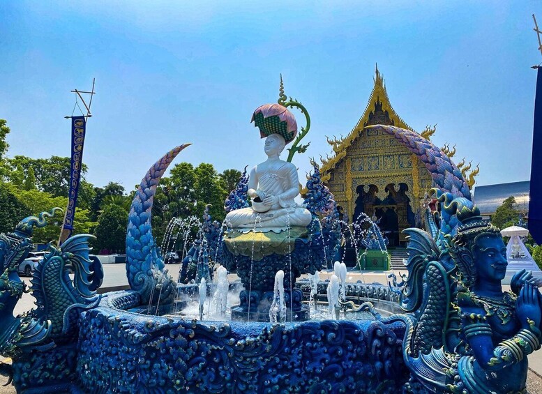 Una gran estatua de Buda en un estanque de loto azul con fuentes ornamentales, rodeada de arquitectura tailandesa tradicional. 5