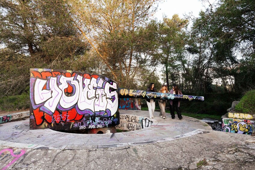 A graffiti-covered concrete structure with people walking around it. 3